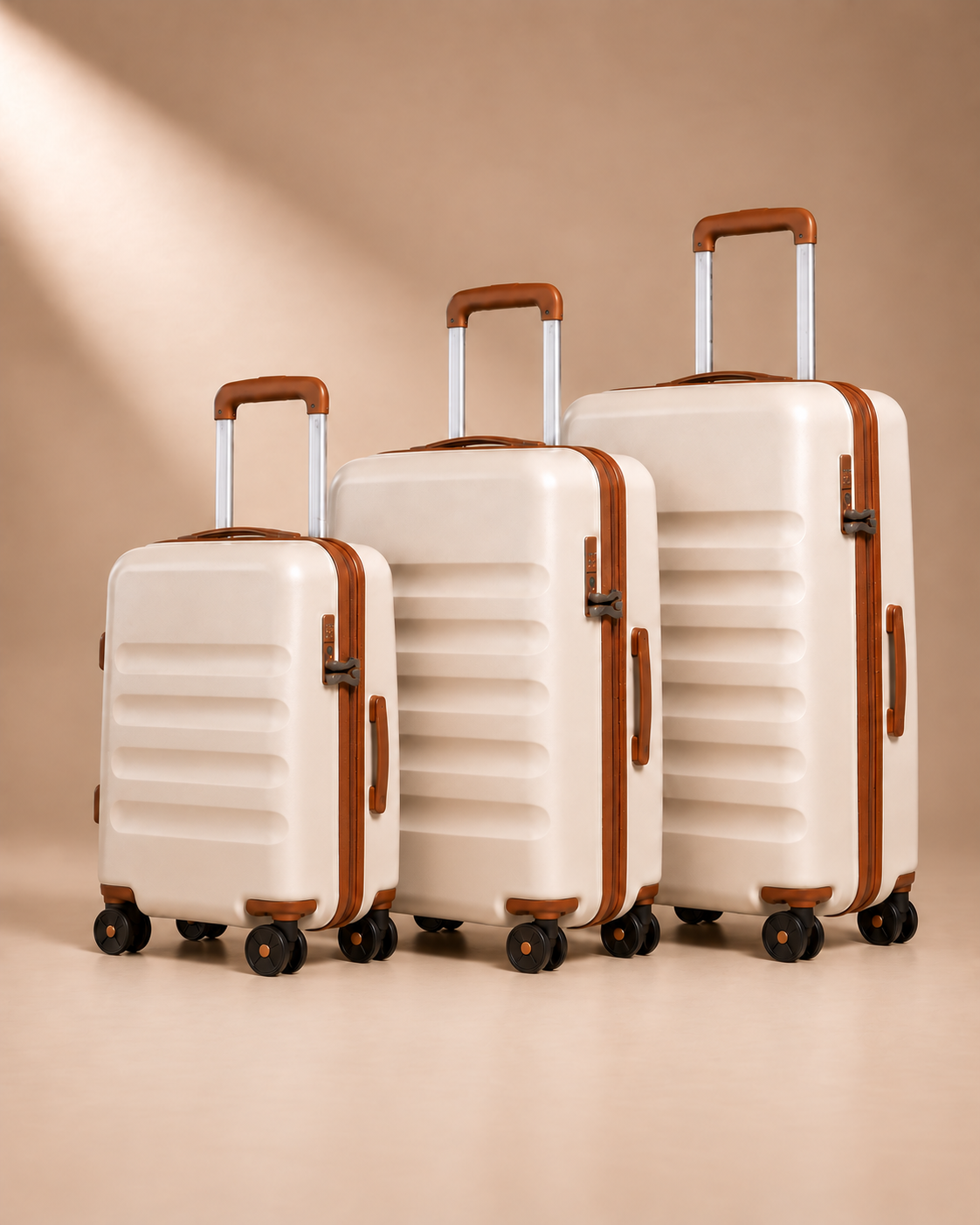 Painswick beige hard-shell suitcases in three sizes, showing telescopic handles, spinner wheels and horizontal shell grooves.