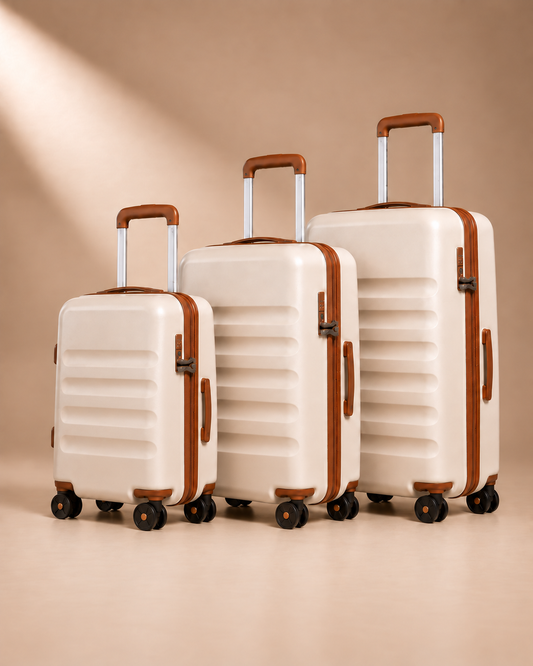Painswick beige hard-shell suitcases in three sizes, showing telescopic handles, spinner wheels and horizontal shell grooves.