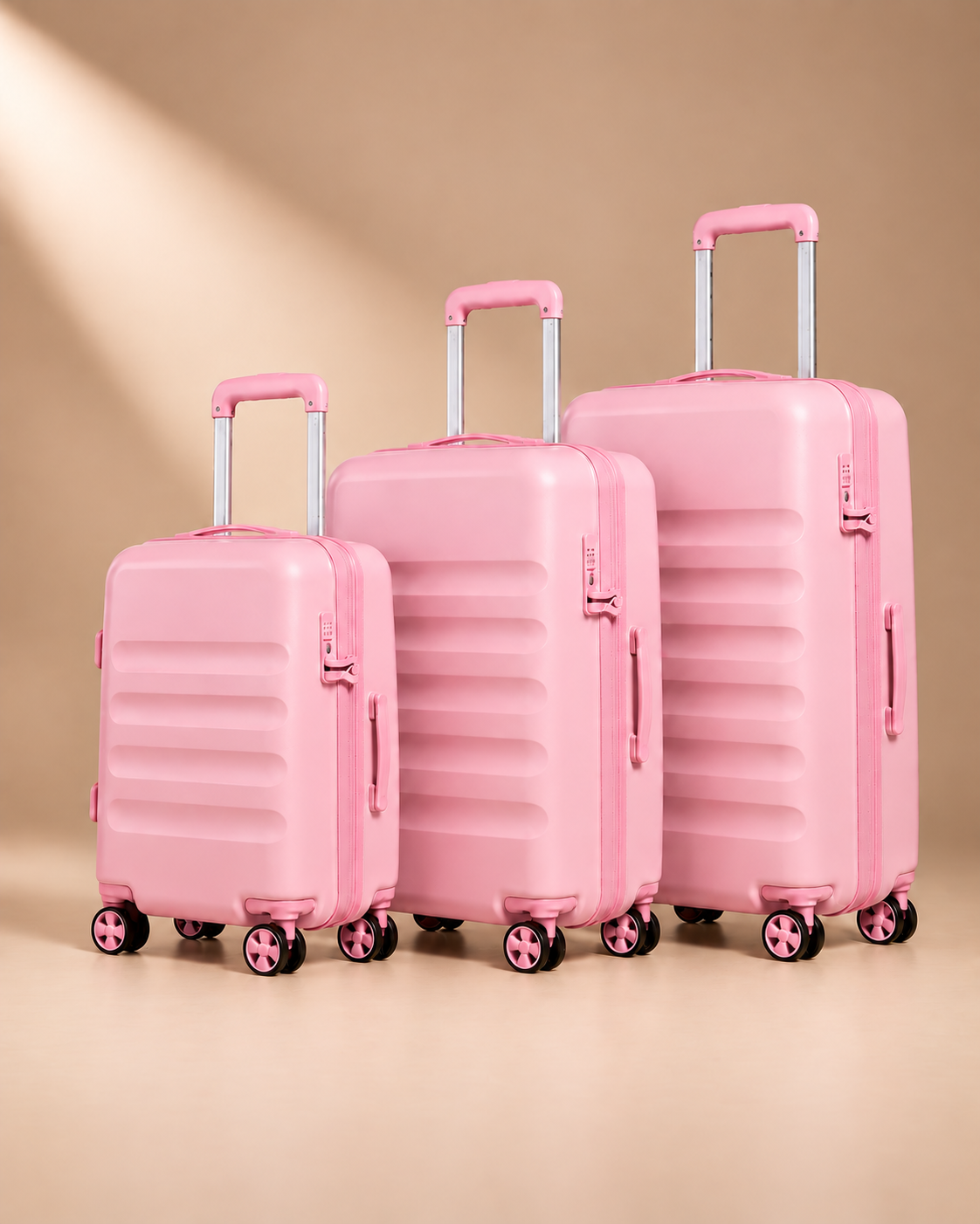 Painswick pink hard-shell suitcases in three sizes, showing telescopic handles, spinner wheels and horizontal shell grooves.